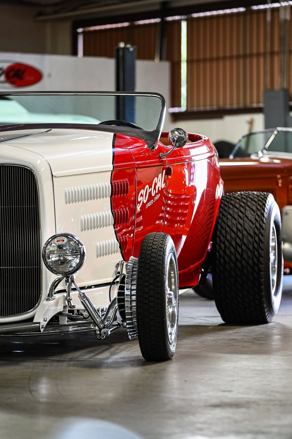Vintage cars in a garage with a red hot rod in the foreground